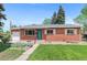 Inviting brick home with a green lawn and well-maintained landscaping, complete with an attached garage at 6025 Johnson Way, Arvada, CO 80004