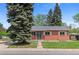 Charming brick home featuring a well-manicured lawn, mature trees, and a welcoming turquoise front door at 6025 Johnson Way, Arvada, CO 80004