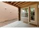 Covered patio featuring exposed beams, stone supports, a door, and a large window to the home's interior at 2940 Ulster St, Denver, CO 80238
