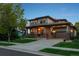 Charming two-story home featuring an inviting front porch and attached garage with manicured lawn, perfect for Gathering living at 12119 S Wanderlust Way, Parker, CO 80138