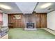 A finished basement featuring a brick fireplace, wood paneling, and green carpeting at 301 S Troy St, Aurora, CO 80012