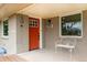Inviting covered front porch with a bright red door, seating and brick facade at 9405 W 54Th Pl, Arvada, CO 80002