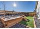 A backyard view with artificial grass and a custom wooden retaining wall with decorative rock, steps, and planter at 17412 W 93Rd Pl, Arvada, CO 80007
