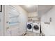 A well-lit laundry room boasts modern, front-loading washer and dryer units with storage at 2230 Miller Ct, Lakewood, CO 80215