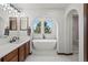 Bright bathroom boasts a soaking tub, white marble floors, and arched entry to the shower at 2980 Craig Ct, Castle Rock, CO 80109