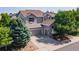 Exterior view of home featuring a three-car garage, lush trees, and a well-manicured lawn at 2980 Craig Ct, Castle Rock, CO 80109