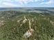 Elevated view of a residence with surrounding forest and a distant view of rolling hills at 2785 Magpie Ln, Larkspur, CO 80118