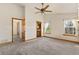 Spacious bedroom with neutral carpet, ceiling fan, views into bathroom, and a window with backyard views at 2785 Magpie Ln, Larkspur, CO 80118