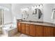 Bright bathroom with double vanity, granite countertops, oval mirrors, and a tiled soaking tub at 7276 Brighton Ct, Castle Pines, CO 80108