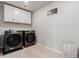 Bright laundry room featuring modern appliances, white cabinets, and light wood-look flooring at 23998 E Atlantic Pl, Aurora, CO 80018