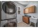 Functional laundry room equipped with stacked washer/dryer, storage cabinets, sink, and neutral tile flooring at 18150 Bolero Dr, Parker, CO 80134