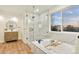 Luxurious bathroom with a freestanding tub, glass shower, marble tiling, wood vanity, and a large window at 8898 Chestnut Hill Ct, Highlands Ranch, CO 80130