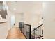Upstairs hallway with metal railing, hardwood floors, and pendant lighting leading to a brightly lit upstairs at 8898 Chestnut Hill Ct, Highlands Ranch, CO 80130