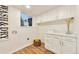 Functional laundry room with white cabinetry, countertop space, window, hardwood floors, and 
