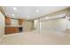 Spacious carpeted basement with a wet bar with dark wood cabinetry and bar fridge, stairs to upper level, and beige walls at 5150 Morning Glory Pl, Highlands Ranch, CO 80130