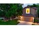 Inviting two-story home with lush green lawn and mature trees, accented by warm exterior lighting at 5150 Morning Glory Pl, Highlands Ranch, CO 80130
