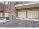Attached garages with white doors and air conditioning units next to the asphalt driveway at 3872 S Dallas St # 7-304, Aurora, CO 80014