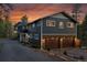Charming home exterior with two-car garage, stone accents, and beautiful sunset at 4574 Picutis Rd, Indian Hills, CO 80454