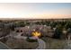Stunning aerial view of a luxury home with a circular driveway and a scenic mountain backdrop at sunset at 4041 E Forbes Ct, Greenwood Village, CO 80121
