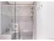 Walk-in shower featuring glass door, neutral-toned tiling, a built-in bench, and modern shower fixtures at 4041 E Forbes Ct, Greenwood Village, CO 80121