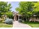 Stately stone home with lush landscaping, mature trees, and a curved driveway leading to the entrance at 4041 E Forbes Ct, Greenwood Village, CO 80121