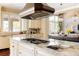 Gourmet kitchen island featuring granite countertops, stainless gas cooktop, and a farmhouse sink with custom cabinets at 4041 E Forbes Ct, Greenwood Village, CO 80121