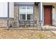 Close-up of a covered porch with outdoor seating, stone detail, and a brick pathway at 193 Ambrose St, Erie, CO 80516