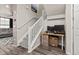 Hallway staircase features gray carpet steps, white railing, and an office desk set under the stairs at 193 Ambrose St, Erie, CO 80516