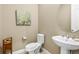 Powder room featuring a pedestal sink, elegant fixtures, neutral tones, and tasteful wall art at 7408 Xenophon St, Arvada, CO 80005