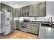 Well-lit kitchen boasts stainless steel appliances, gray cabinets, and tiled floors at 5487 Balsam Ct, Arvada, CO 80002