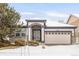 Charming single-story home featuring stone accents, a two-car garage, and a well-maintained front yard with winter snow at 23612 E Mississippi Cir, Aurora, CO 80018