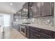 Modern kitchen with dark cabinets, herringbone backsplash, and stainless steel appliances at 12224 Olive Way, Thornton, CO 80602