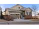 Inviting home with a two-car garage, stone accents, and neutral-colored siding surrounded by a well-kept lawn and street view at 9587 Kentwick Cir, Englewood, CO 80112