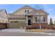 Charming two-story home featuring a stone and siding exterior, a well-manicured lawn, and an attached two-car garage at 9587 Kentwick Cir, Englewood, CO 80112