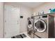 Modern laundry room with stainless steel washer and dryer, storage shelf, and access to the backyard at 5470 S Jasper Way, Centennial, CO 80015