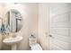Cozy half bathroom with a pedestal sink, decorative mirror, and neutral color scheme at 2243 Villageview Ln, Castle Rock, CO 80104