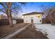 The backyard has a white brick house, a small shed, a tree, and snow on the ground at 1901 S Lincoln St, Denver, CO 80210