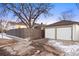 A detached two-car garage next to a wooden fence, with a driveway and snow on the ground at 1901 S Lincoln St, Denver, CO 80210