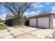 Two-car garage with a large parking pad beside a tall, dark fence and mature landscaping at 1901 S Lincoln St, Denver, CO 80210