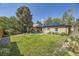 Expansive backyard with a lush lawn, mature trees, a patio area, and solar panels on the roof at 2844 Bellaire St, Denver, CO 80207