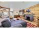 Open-concept living room with wood paneling, stone fireplace, and adjacent kitchen area at 2844 Bellaire St, Denver, CO 80207