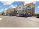 Three-story condo building featuring balconies, brick facade, and ample parking at 3890 S Dayton St # 105, Aurora, CO 80014