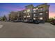 A stunning exterior view of the condo building at dusk, showcasing the brick facade and balcony features at 3890 S Dayton St # 105, Aurora, CO 80014