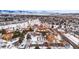 An aerial view showcases a community with snow-covered buildings and trees, set against a backdrop of distant mountains at 3305 S Ammons St # 202, Lakewood, CO 80227