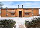Two-story exterior featuring twin chimneys, balconies, and a snow-covered courtyard with green shrubs at 3305 S Ammons St # 202, Lakewood, CO 80227