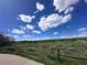 Scenic view featuring a lush green field with a fence and blue sky with fluffy clouds above at 3305 S Ammons St # 202, Lakewood, CO 80227