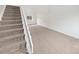 Open living area with a staircase featuring neutral carpet and a large window at 5785 S Lisbon Way, Centennial, CO 80015