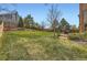 Large grassy backyard features a deck, mature trees, and a privacy fence at 1604 Brookside Dr, Highlands Ranch, CO 80126