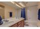 Bathroom with double sinks, a bathtub with shower, and wood cabinets at 1604 Brookside Dr, Highlands Ranch, CO 80126