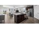 Open floor plan featuring a modern kitchen with stainless steel appliances and an island connected to the living room at 401 Clubhouse Dr, Fort Lupton, CO 80621